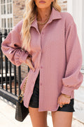 Person wearing a pink cable knit cardigan with a blurred background
