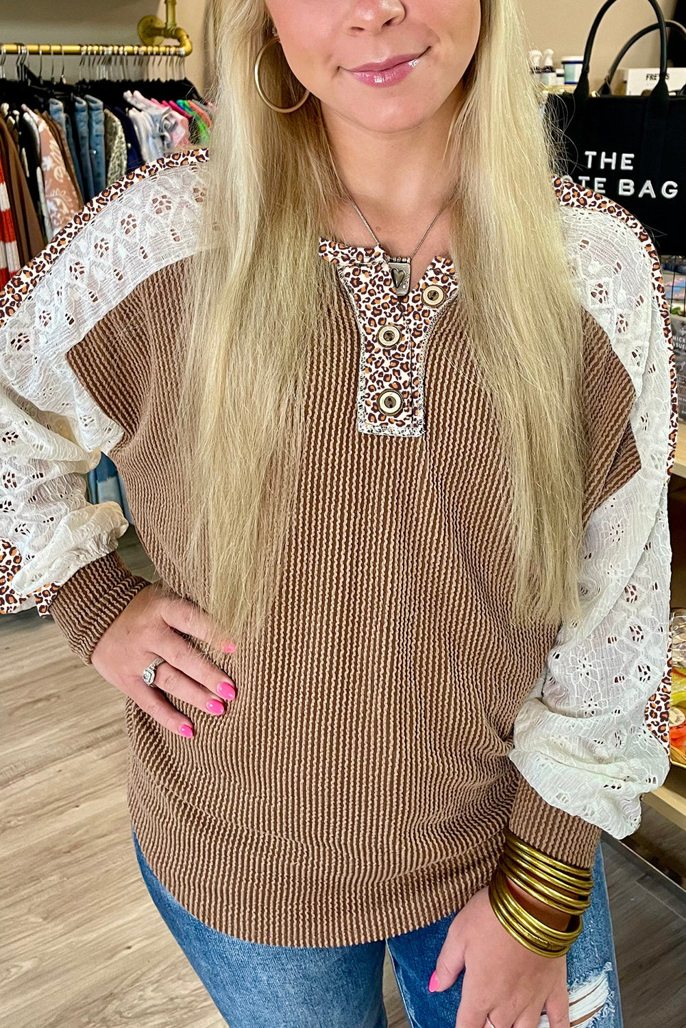 Woman wearing a brown sweater with lace sleeves in a store setting
