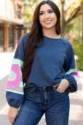 Woman wearing a navy sweater with colorful sleeves outdoors