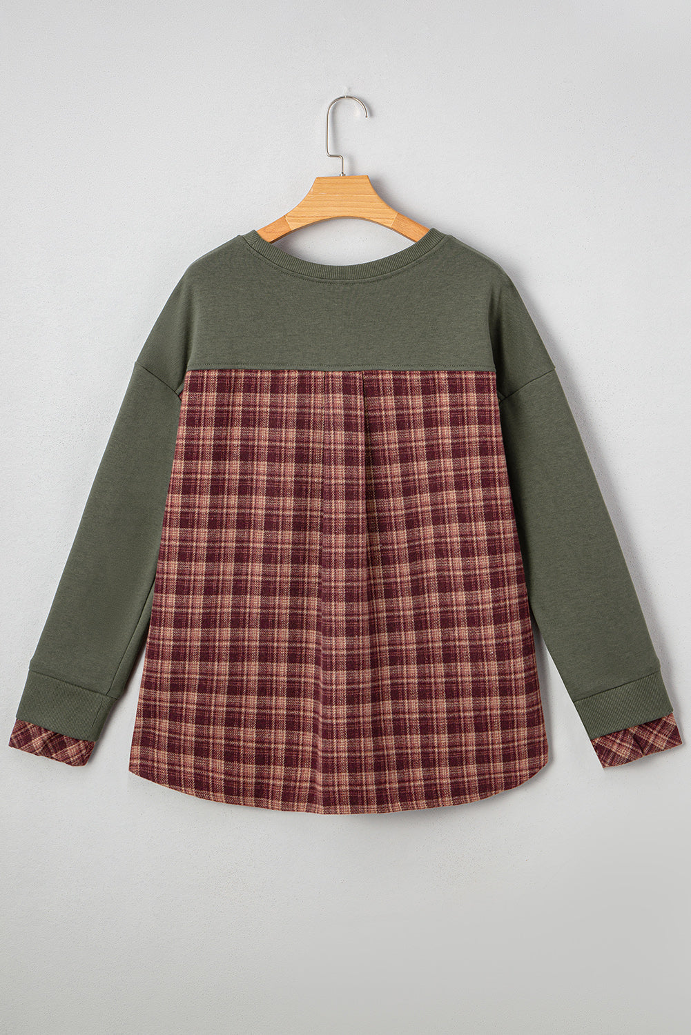 Green long-sleeve shirt with plaid pattern on a hanger against a gray background
