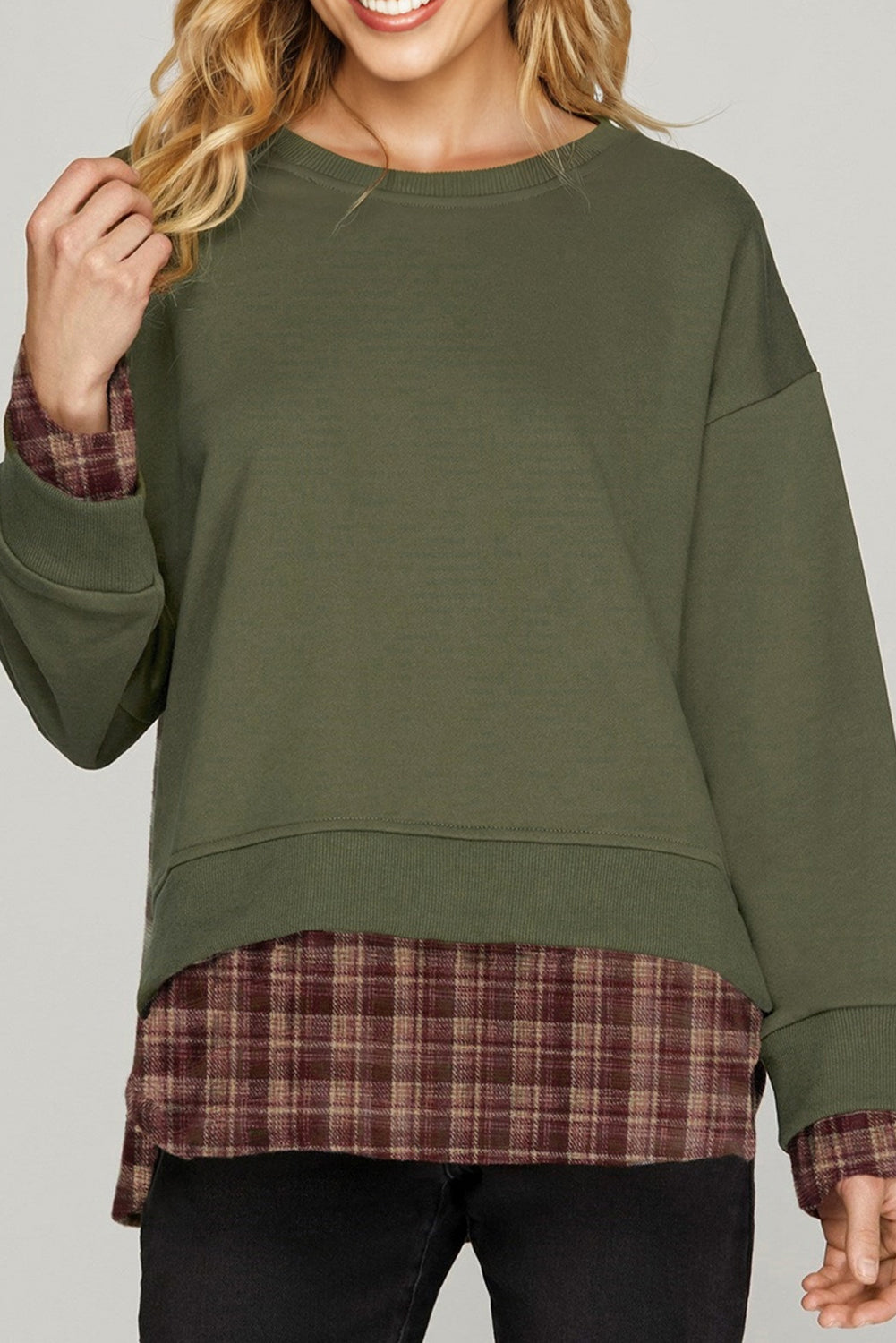 Green sweatshirt with plaid trim worn by a person on a gray background