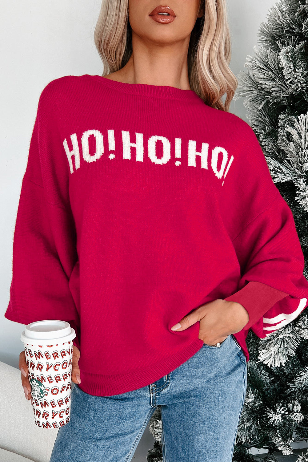 Person wearing a red 'HO! HO! HO!' sweater with a Christmas tree in the background