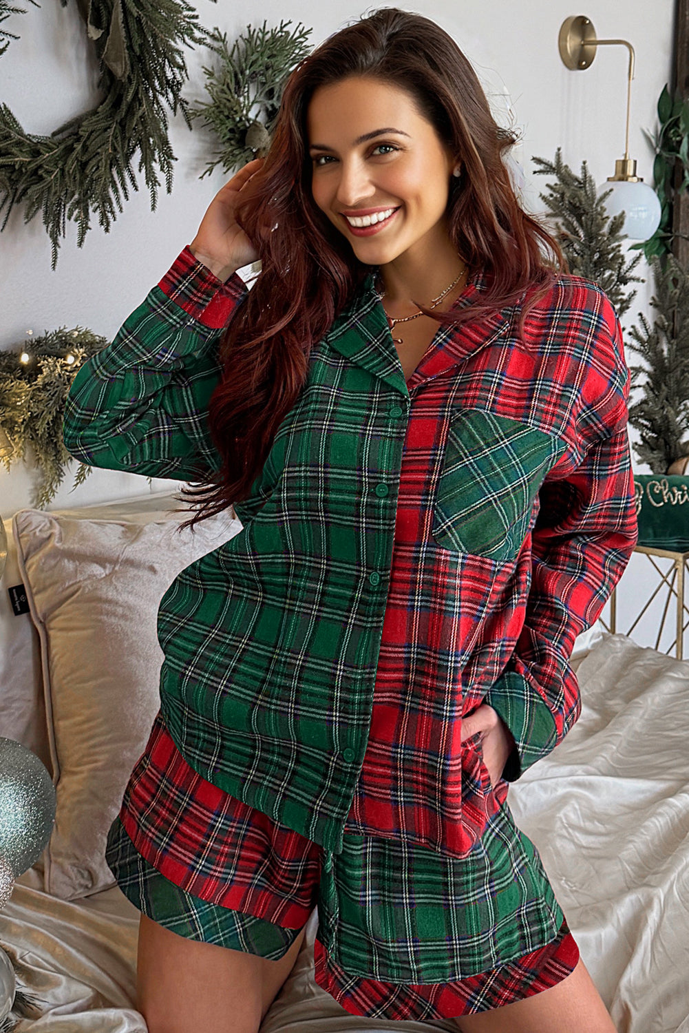 Woman wearing a red and green plaid pajama set in a festive bedroom setting.